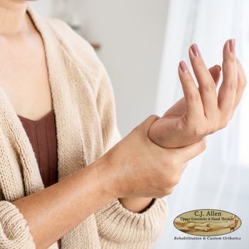 A person holds their right wrist with their left hand, possibly indicating wrist pain. The logo for C.J. Allen Rehabilitation & Custom Orthotics appears in the bottom right corner. A person holds their right wrist with their left hand, possibly indicating wrist pain The logo for C J Allen Rehabilitation & Custom Orthotics appears in the bottom right corner