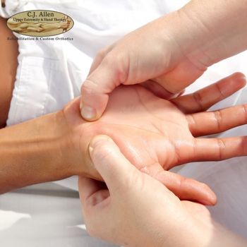 A therapist uses both hands to apply pressure to a person's palm during a hand therapy session. A therapist uses both hands to apply pressure to a person's palm during a hand therapy session